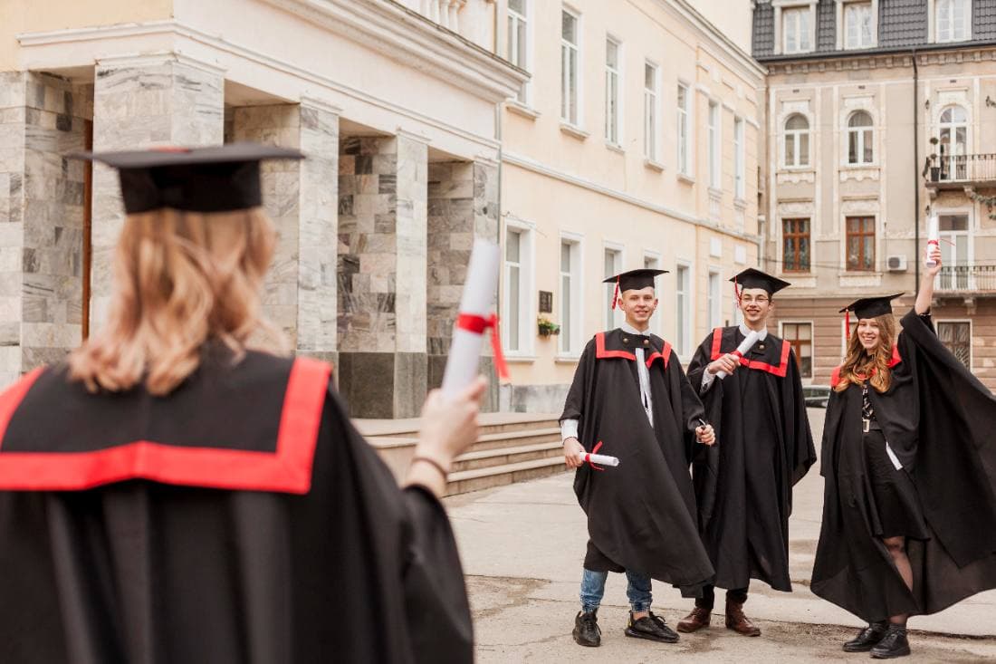 Graduates in caps and gowns hugging outside after the ceremony